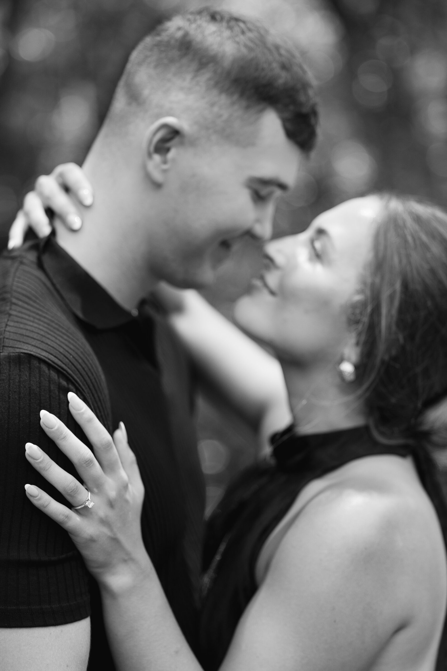 A newly engaged couple lean in for a kiss in a garden in black and white engagement photos Wilmington NC