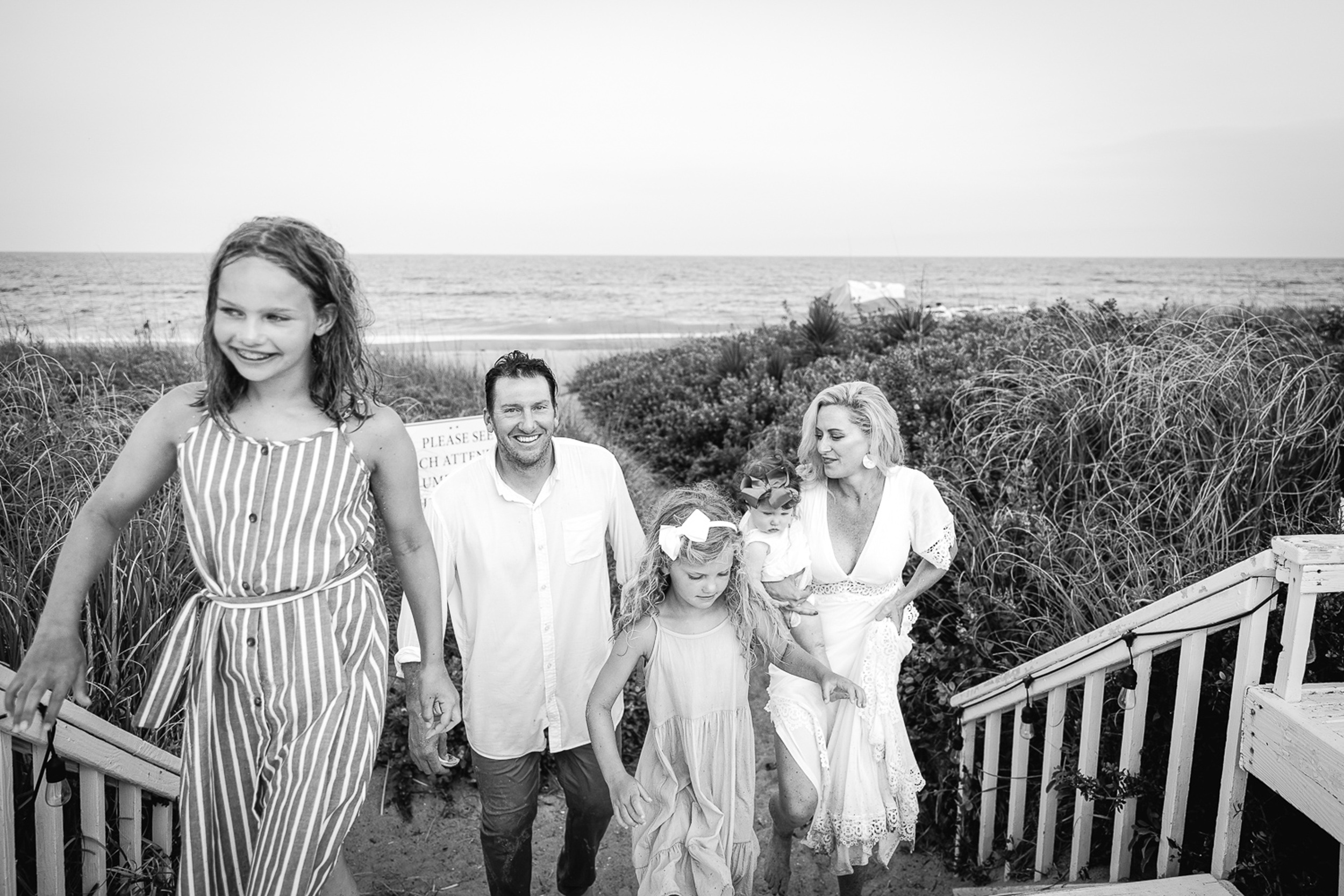 A young family of 5 walk up a beach boardwalk together while doing things to do in wilmington with kids