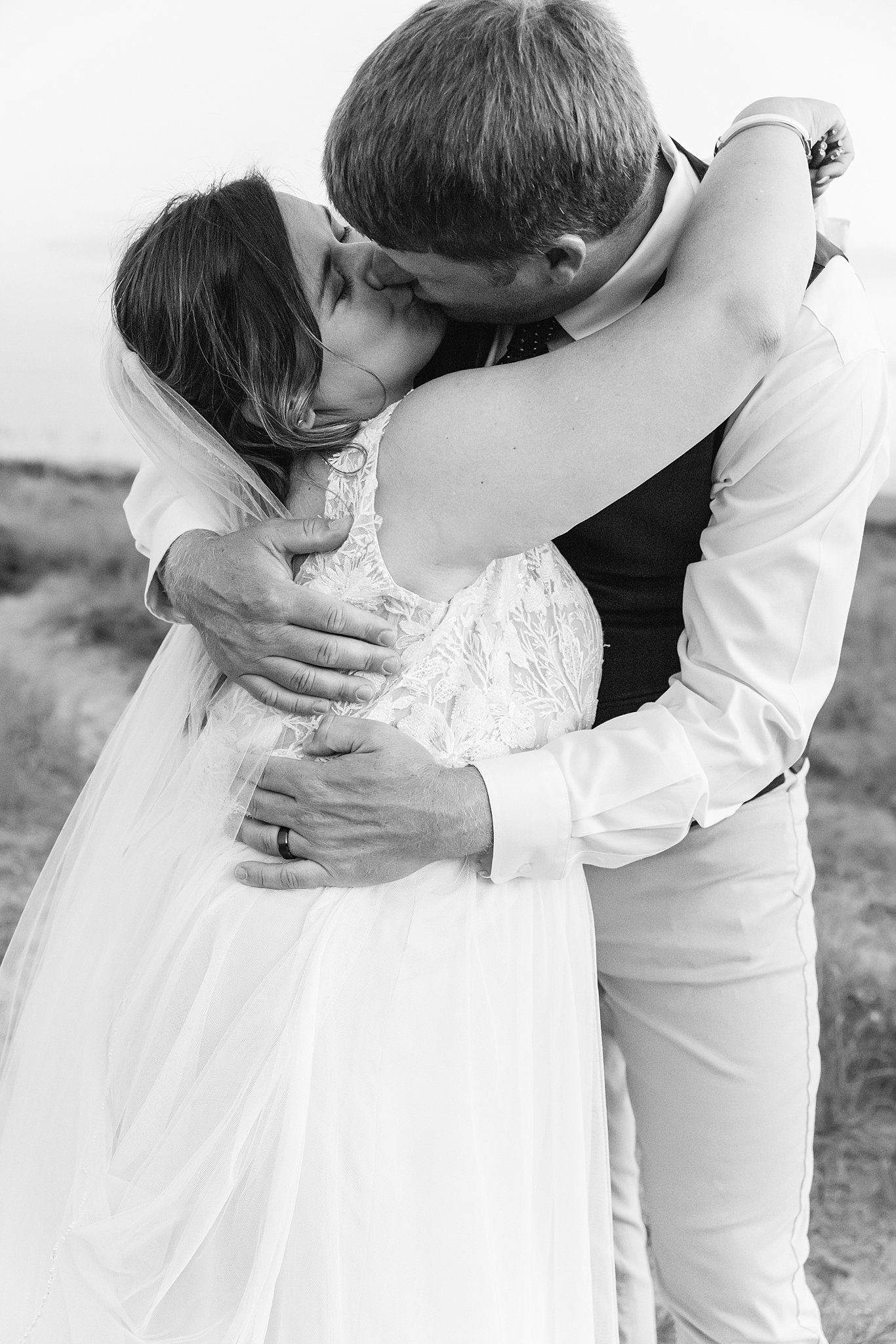 Newlyweds embrace for a big kiss on the beach at sunset