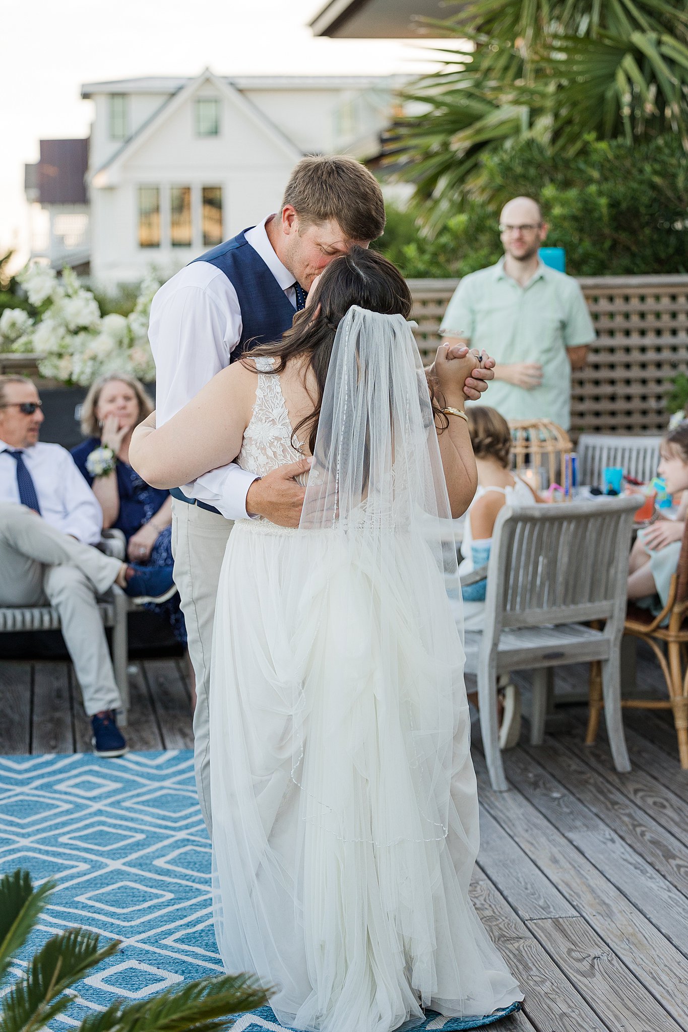 Newlyweds kiss during their first dance on a beachfront deck during their wrightsville beach wedding and elopement