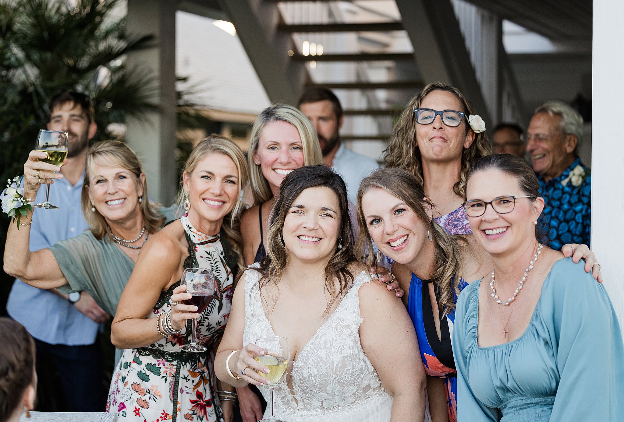 A bride is surrounded by family and friends while celebrating on a deck