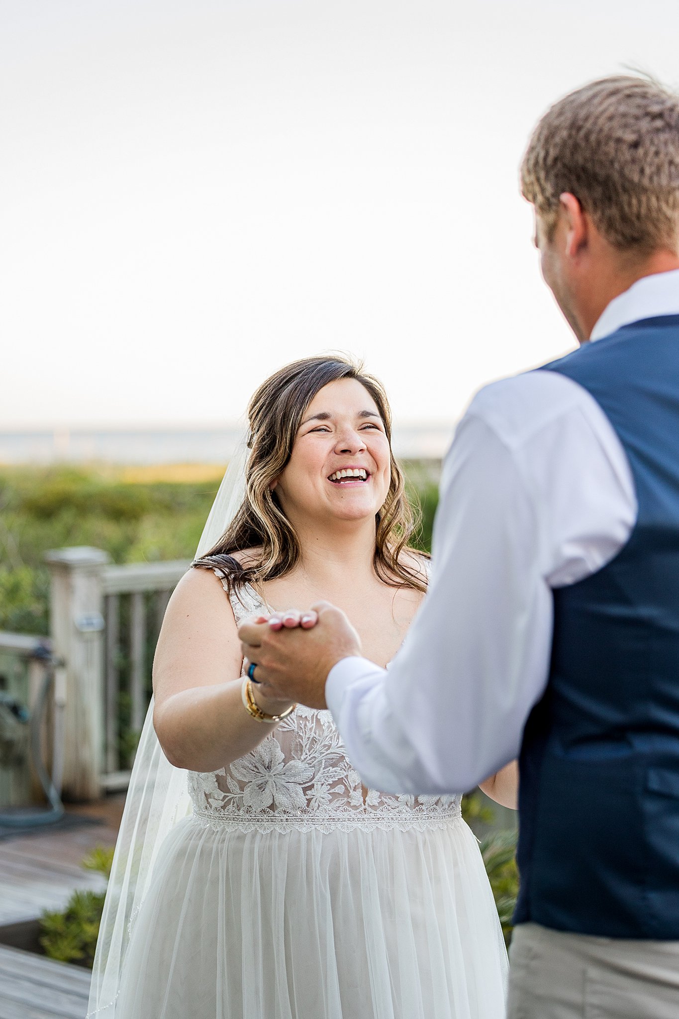 A bride laughs while dancing with her groom on a boardwalk during their wrightsville beach wedding and elopement