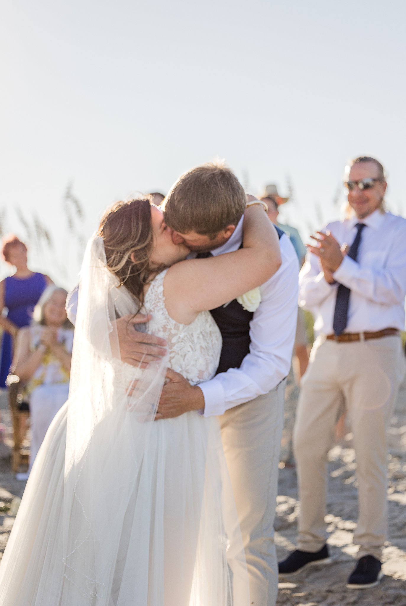 Newlyweds kiss on a beach at sunset to end their beach ceremony