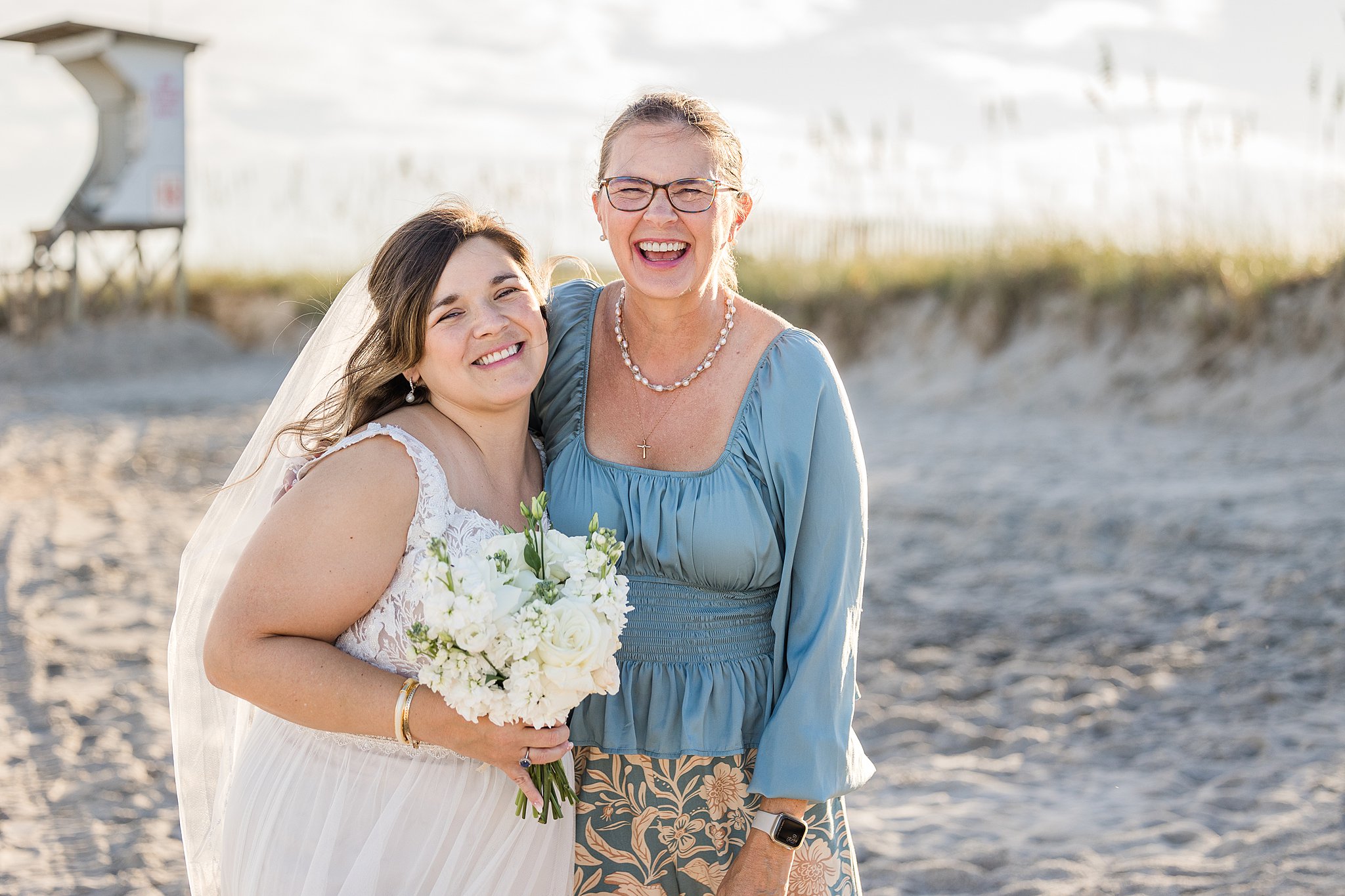 A bride laughs while hugging mom at sunset during her wrightsville beach wedding and elopement