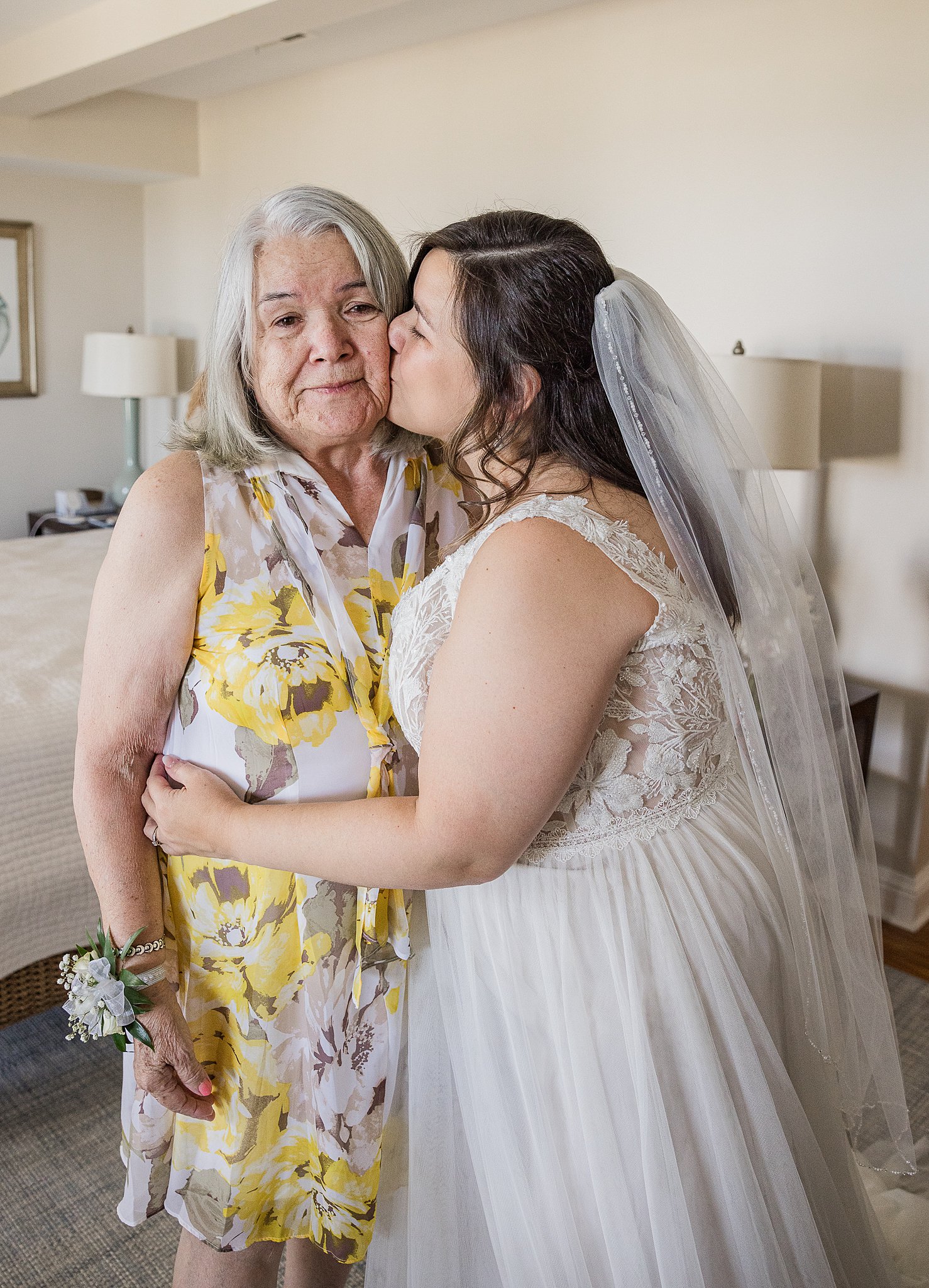 A bride kisses her grand mother while standing in the getting ready room