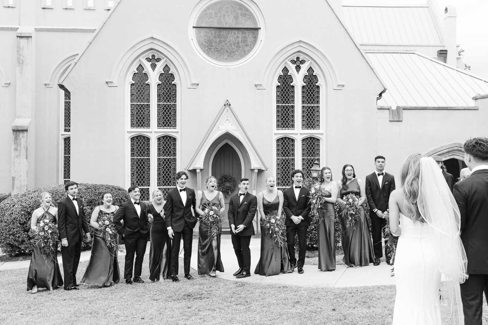 A large wedding party reacts to seeing the bride and groom before their Bakery 105 wedding