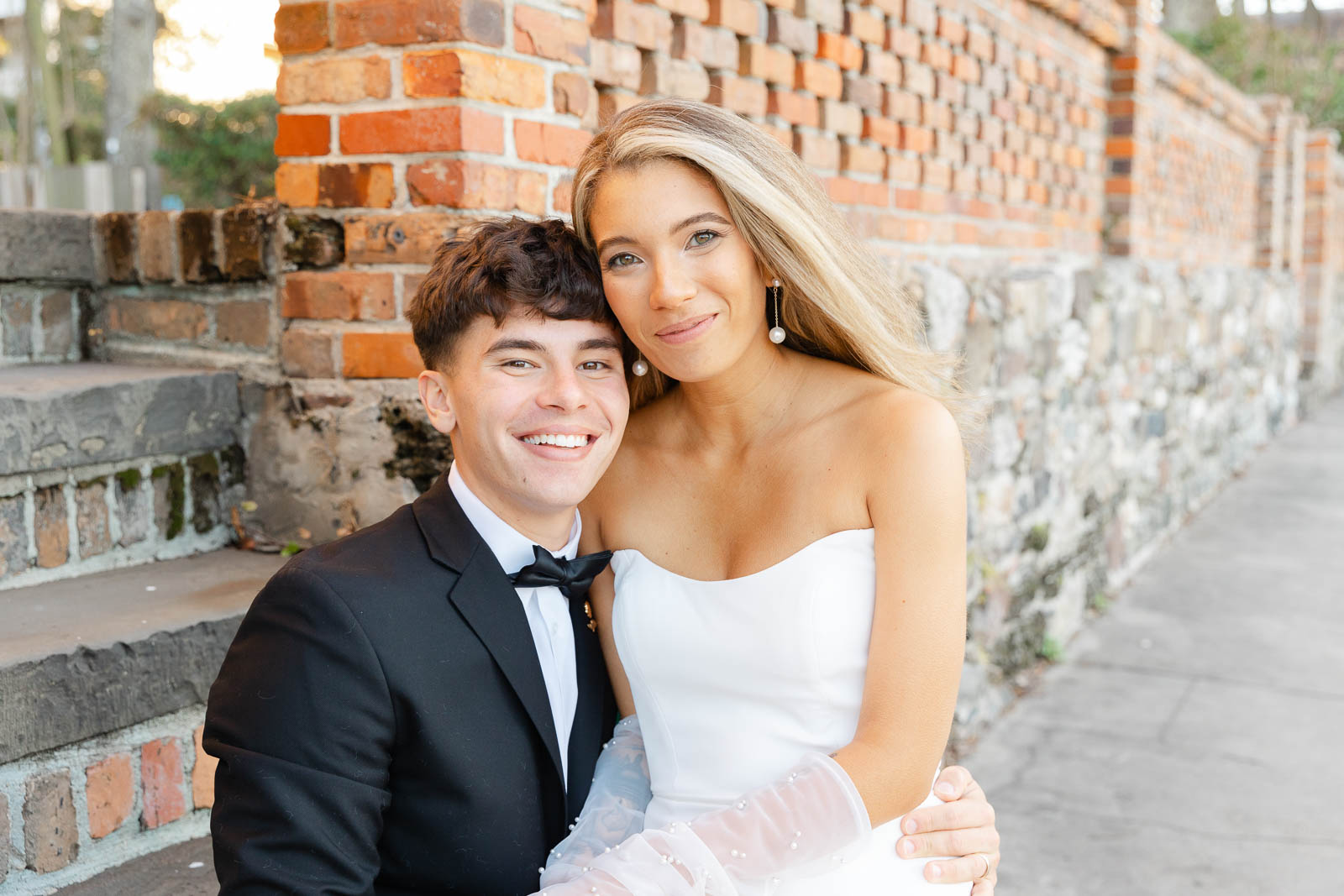 Newlyweds snuggle while sitting on old brick steps during their Bakery 105 wedding