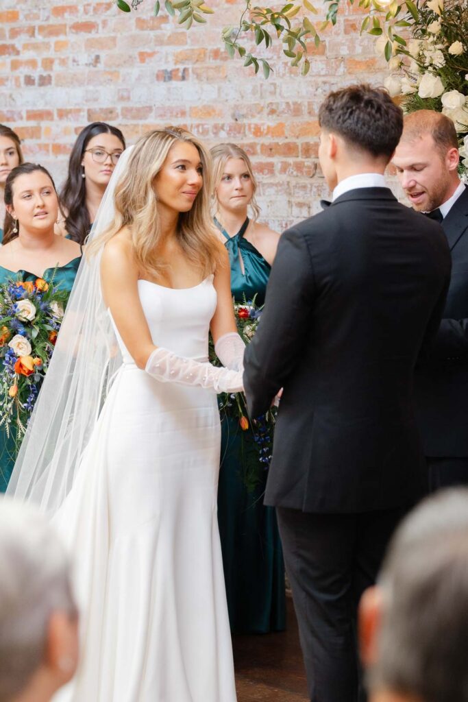 Newlyweds smile at each other while holding hands during their ceremony