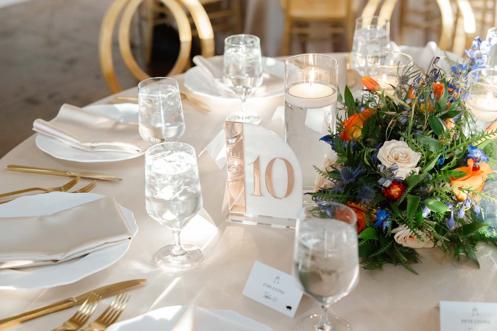 Details of a table setting with a colorful floral centerpiece and gold silverware